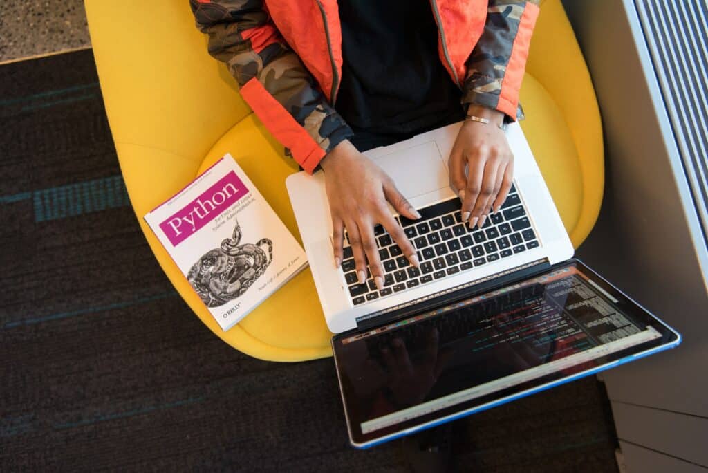 personne en train d'apprendre le langage Python sur son ordinateur portable grĂące Ă un livre